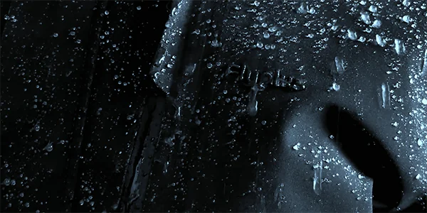 Primo piano del tessuto impermeabile per esterni con gocce d'acqua, che rappresentano il rivestimento DWR e la tecnologia delle cuciture sigillate di WHFrontend per una resistenza all'acqua duratura.