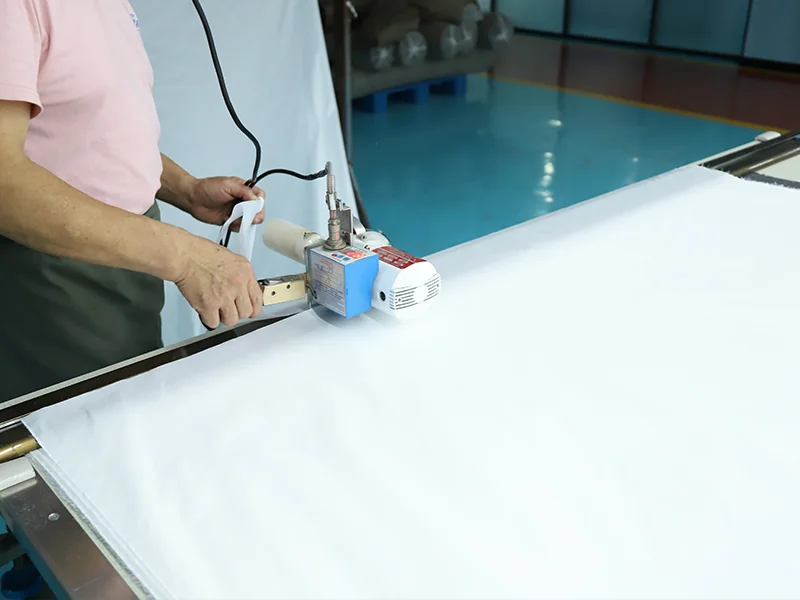 Worker inspecting and cutting fabric before garment production, representing WHFrontend’s strict quality control in OEM outdoor clothing manufacturing.