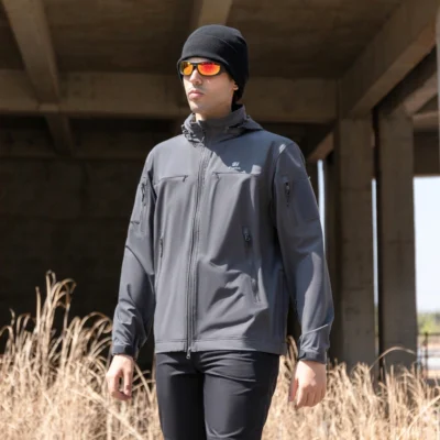 Outdoor model wearing grey lightweight softshell jacket, ideal for hiking, camping, and tactical environments.