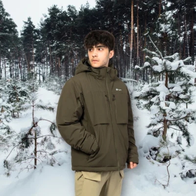 Model wearing waterproof winter jacket in snowy forest, designed for hiking, trekking, and cold climate protection.