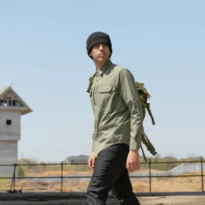 Model wearing army green outdoor shirt while hiking outdoors, showing lightweight and breathable performance.