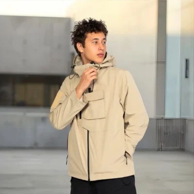 Outdoor photo of khaki waterproof jacket with hood, showing stylish design and durable fabric for hiking or camping.